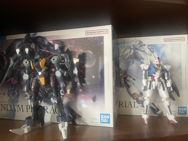 Photo of two toy robots, one purple and one white, sitting on a shelf in front of their boxes.